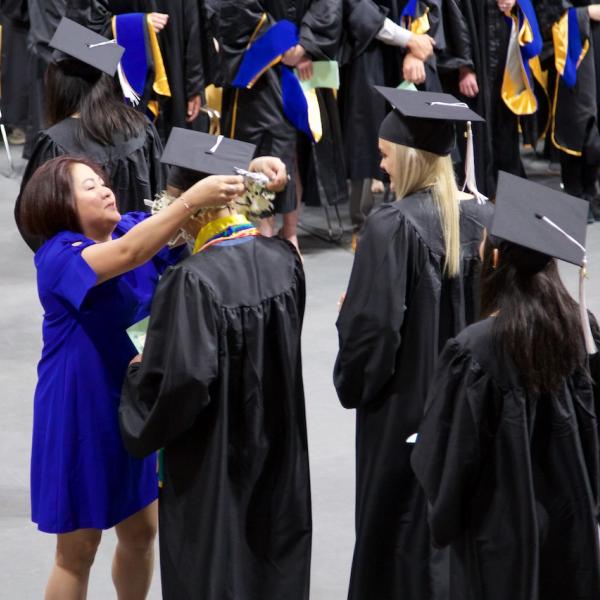 During the processional, a mom takes a quick moment to give her son a lei