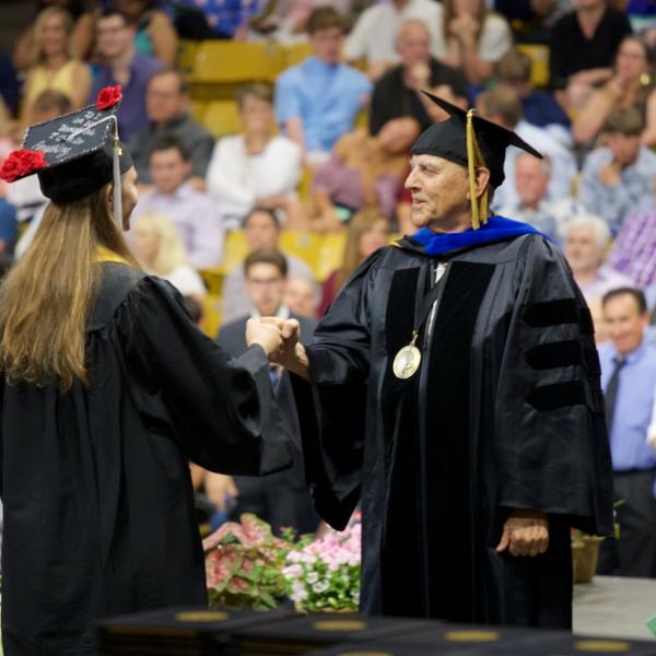 Due to a cold, the chair fist-bumped the graduates as they crossed the stage rather than shaking their hands