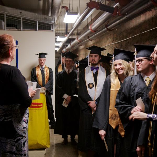 In the underbelly of Macky, the undergraduates line up for the processional and undergraduate advisor Laurel Amsel tells them how it's going down