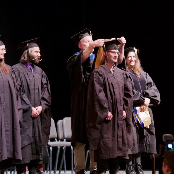 Three students received their Master's in the ceremony; here Max Cantor is hooded by Professor Tim Curran