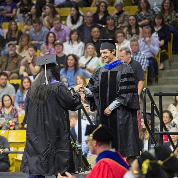 The Chair fist bumps one of the first graduates to cross the stage. Many, many more to come.