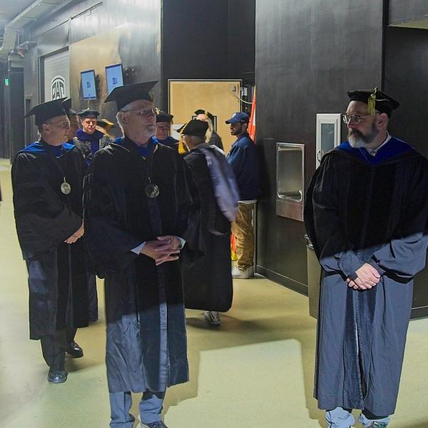 The faculty assemble in a dark corner of the Events Center for the processional