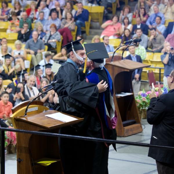 Emcee Lew Harvey embraces his son, Sebastian, the psychology graduate