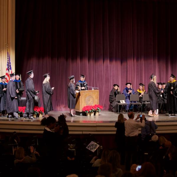 The undergraduates cross the stage for a diploma (cover), handshake, and photo op