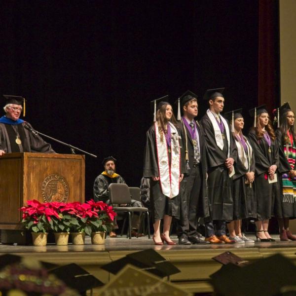 Professor Lew Harvey announces those graduating with Latin honors