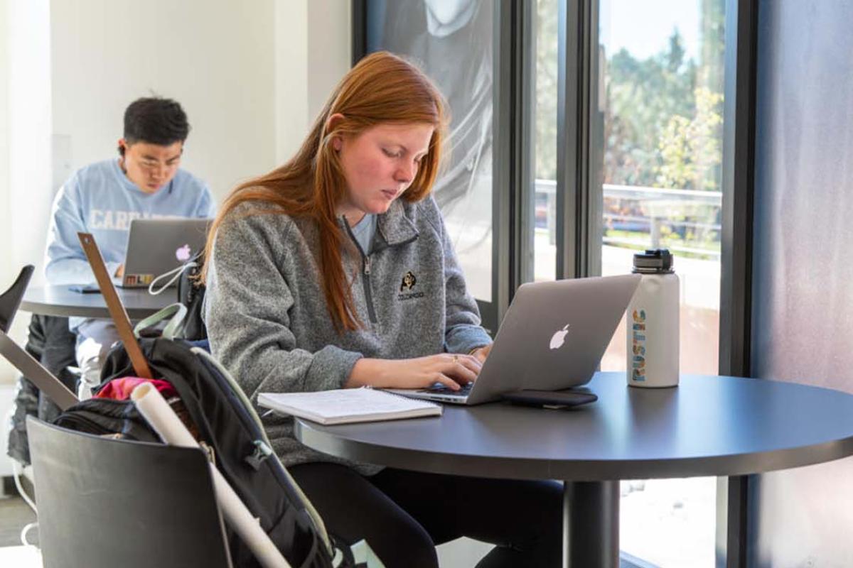 female sitting at table with laptop