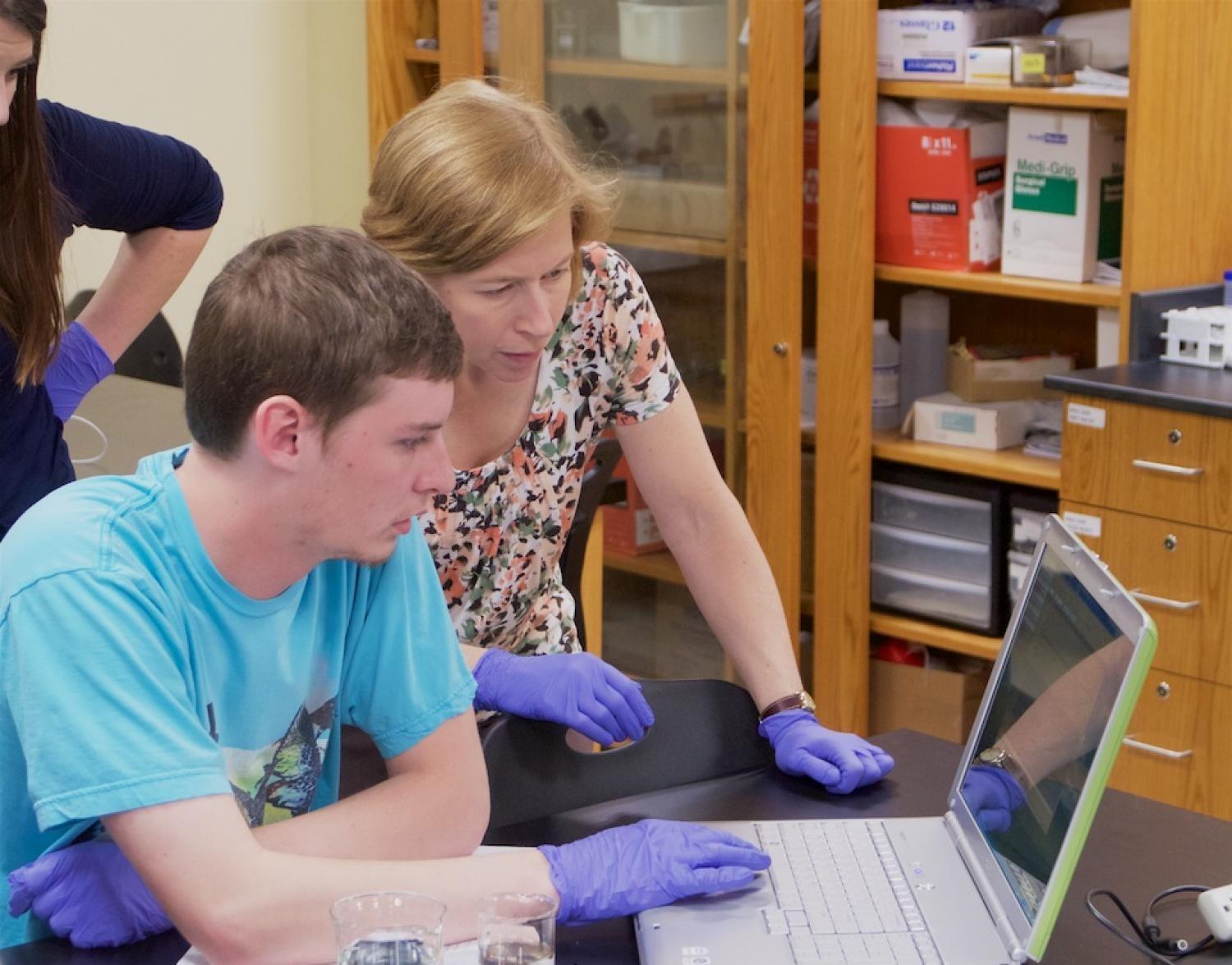 student and professor looking at laptop