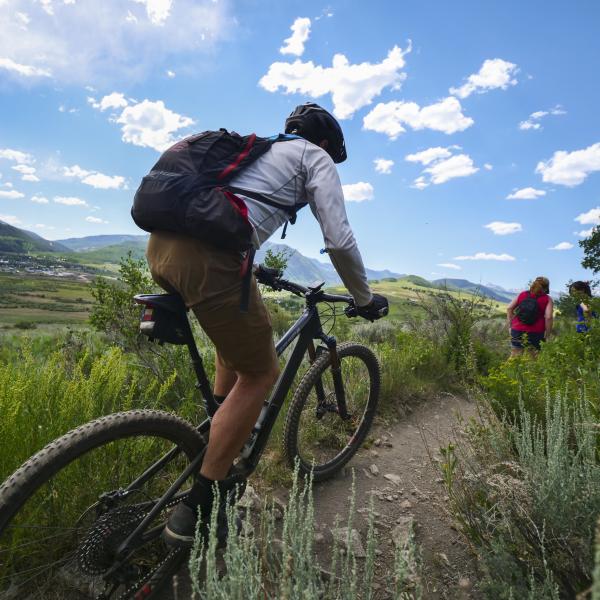 A biker and two hikers on a hiking path