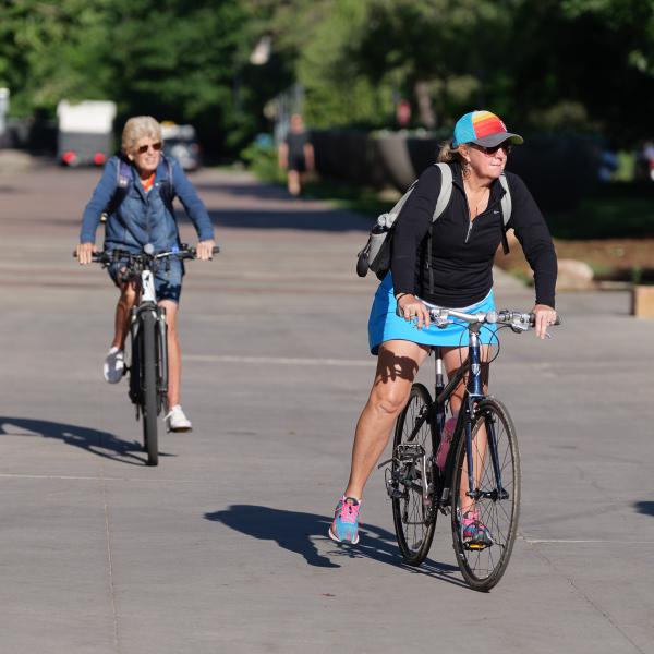 Two cyclists biking on CU Campus