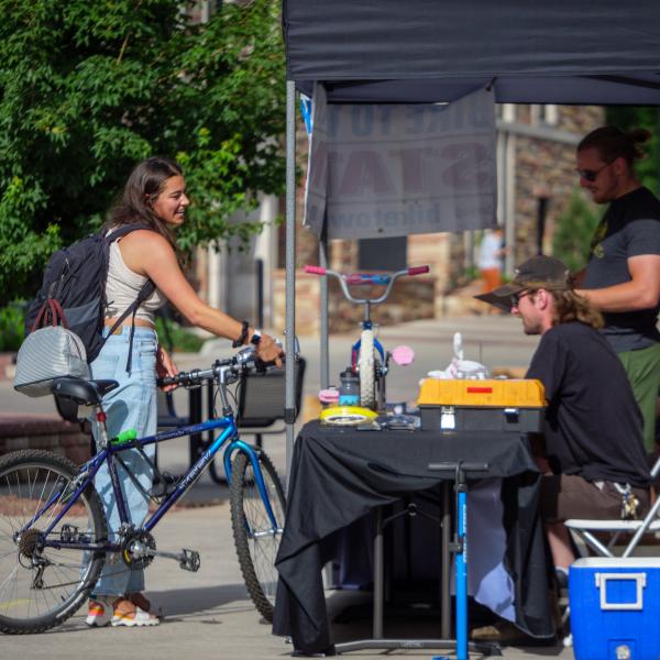 Person on bike stops at the CU Rec Center food station in Boulder during Summer Bike to Work Day 2002