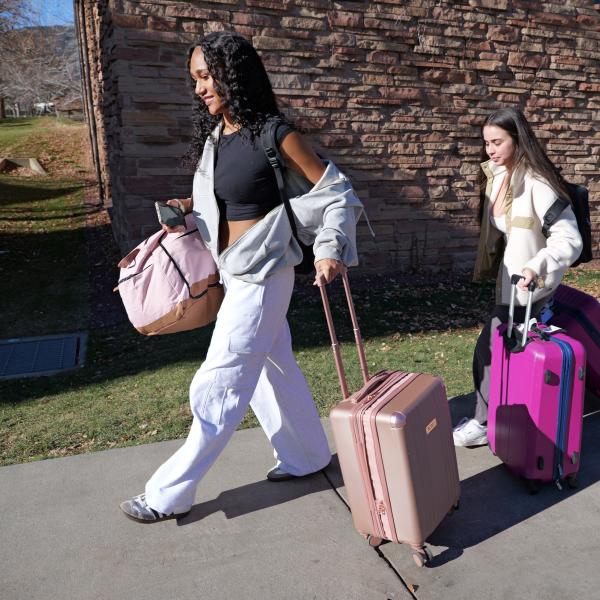 Two students roll their luggage through campus on their way home for the holiday break