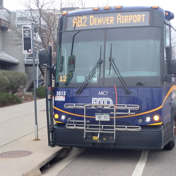 Photo of an RTD bus from the AB2 route parked next to a bus stop.