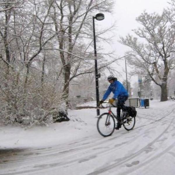 Person riding bicycle on multi-use path in snowy conditions.