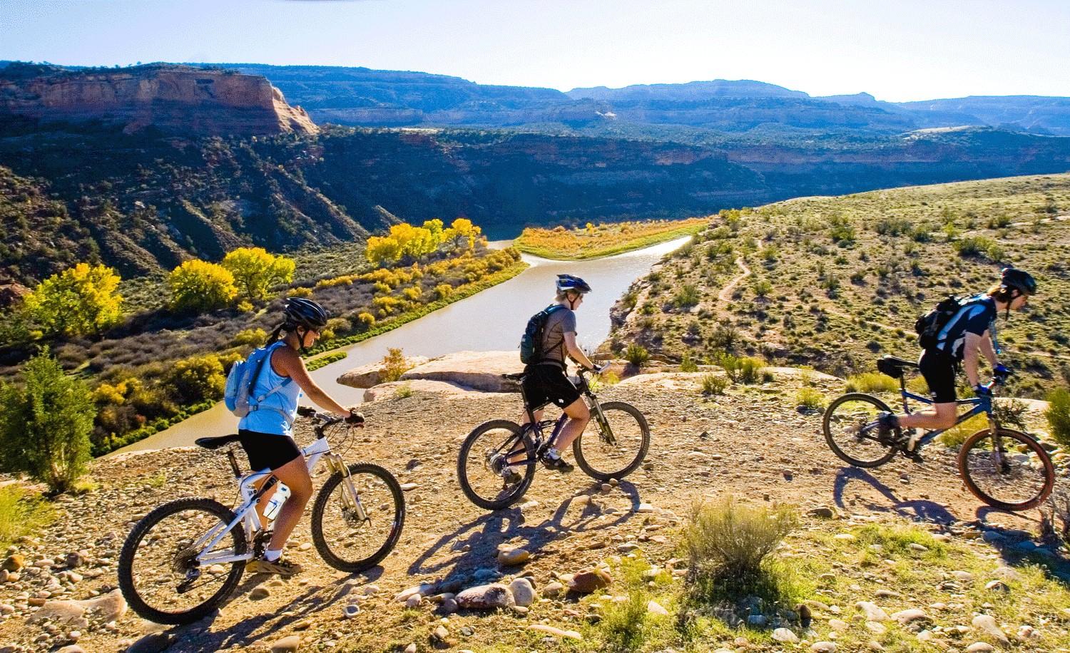 Three friends ride pass a scenic overlook.