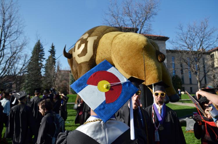 A CU Boulder graduating student wears a cap decorated as the State of Colorado flag.