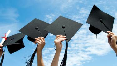 Hands holding graduation caps in the air