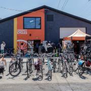 Image of Community Cycles shop with customer gathered in outdoor display area.