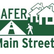 Figure crossing street adjacent to buildings, "Safer Main Streets" in green text.
