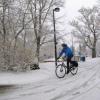 Person riding bicycle on multi-use path in snowy conditions.