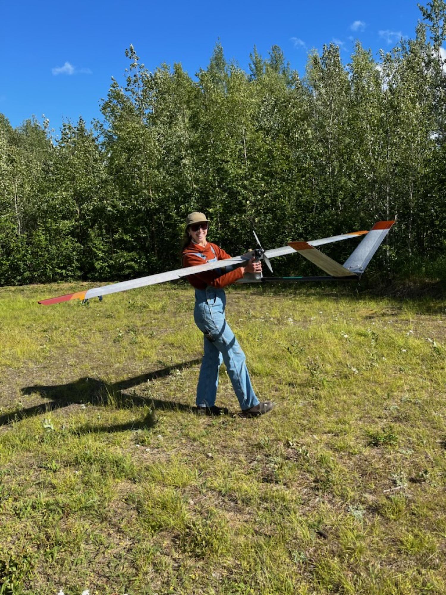 CU Boulder incoming PhD student Paloma Siegel carries an aircraft away from an Alaskan landing strip after flight