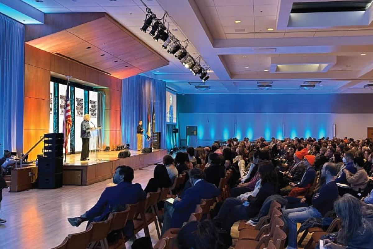 Conference room full of people looking at the speaker on stage