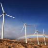 Wind turbines in front of mountains and a rainbow
