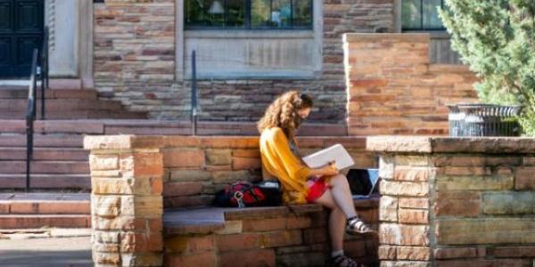 student reading outside a building