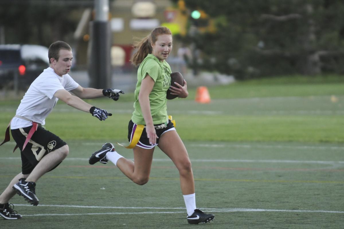 a woman with a football being chased on the playing field