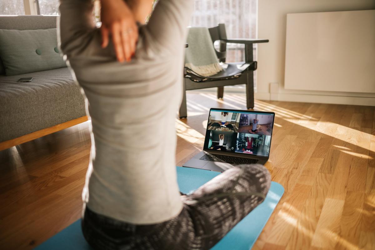 woman working out at home looking at her laptop