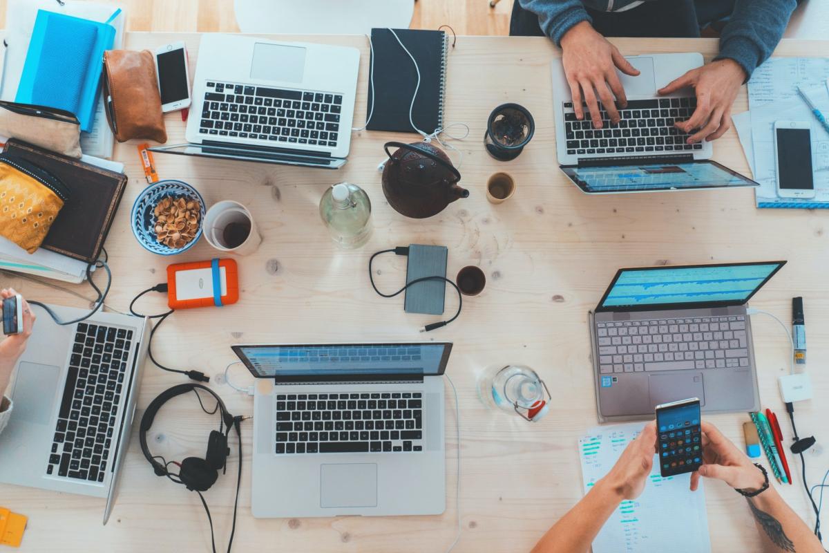 multiple latptops open on a table as people work together