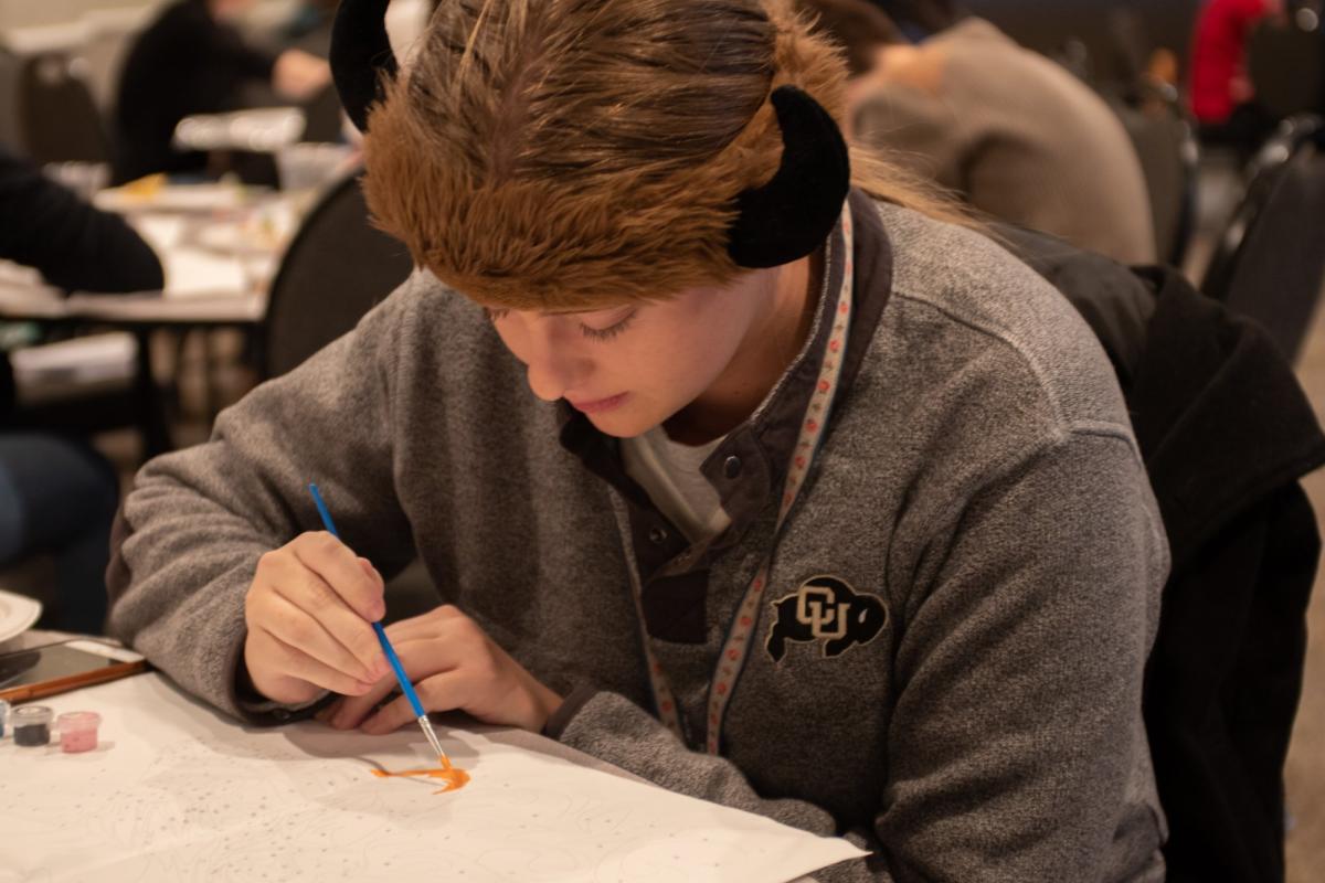 student in CU gear painting