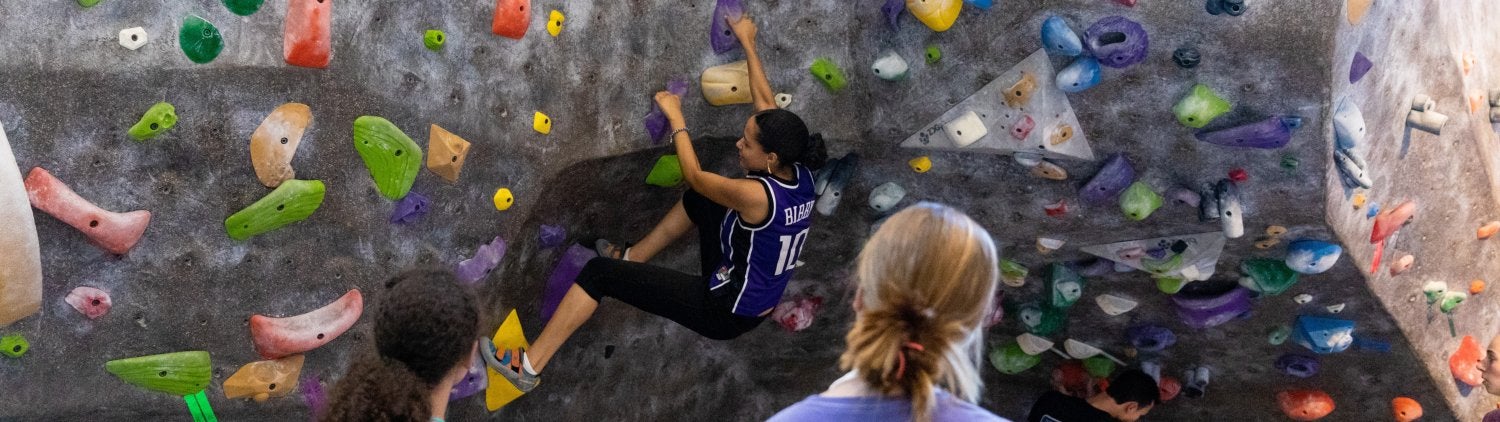 student on the climbing wall as she is being instructed