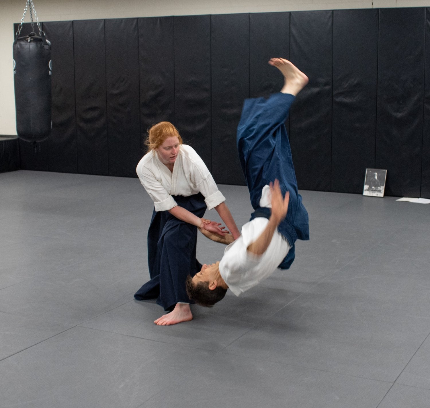 woman tossing a male instructor in an aikido class