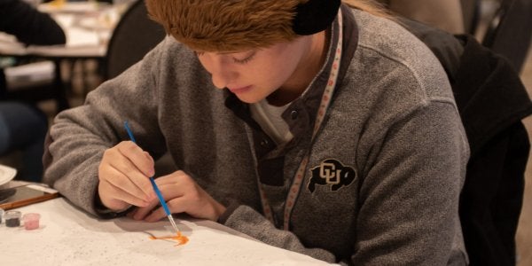 student in CU gear painting