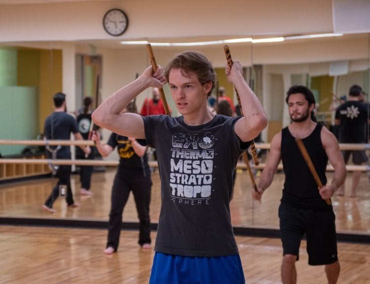 man wielding two narrow sticks as weapons