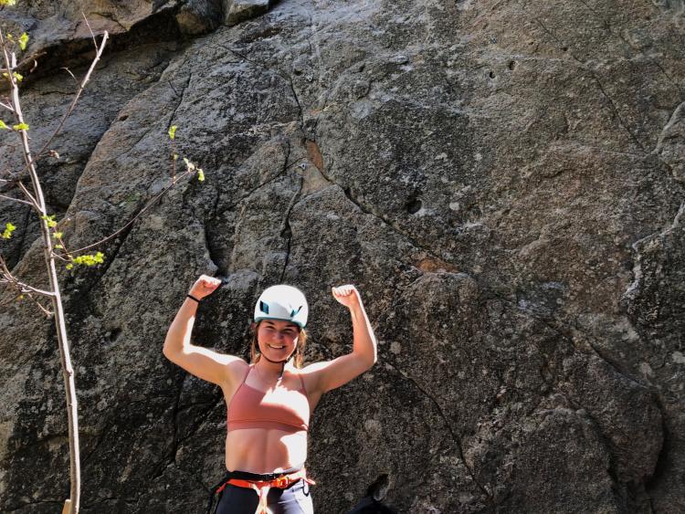 woman in climbing helmet posing triumphantly