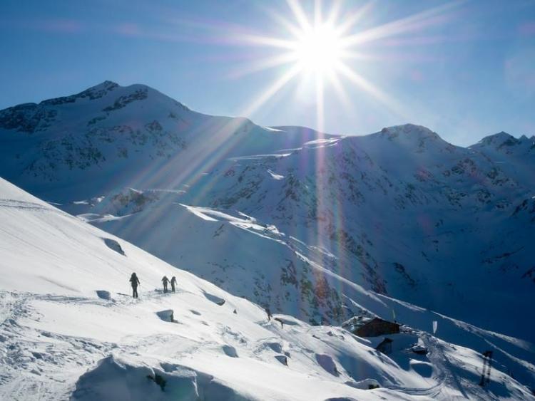 a snowy mountainside dotted with skiers.