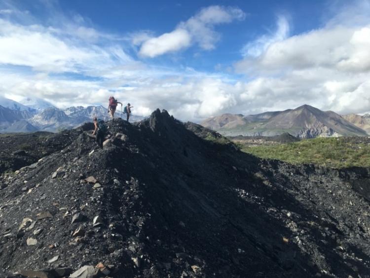 two figures at the top of a glacier ina green landscape