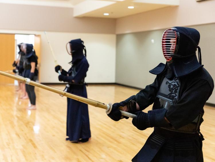student in full protective garb holding a kendo stick