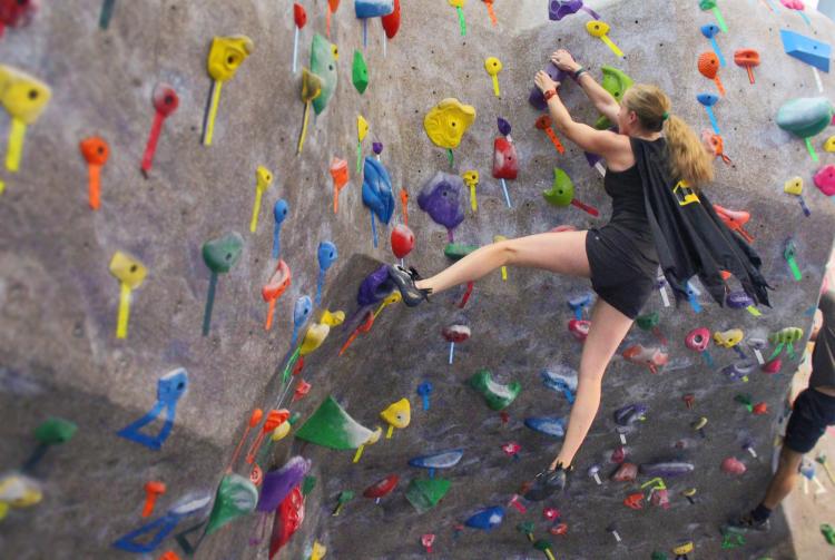 woman in a batman cape climbing a wall