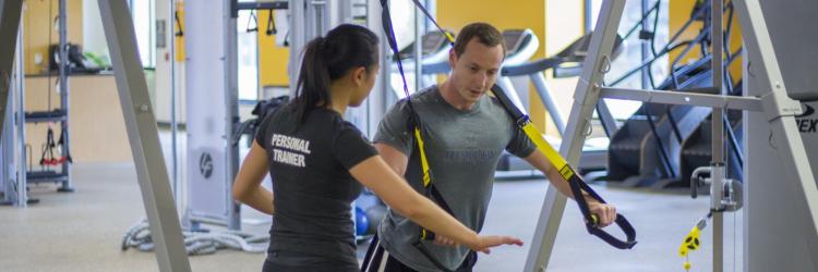 Personal trainer working with client on TRX ropes