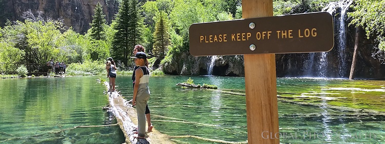 People walking on log next to Please Keep Off the Log sign at Hanging Lake