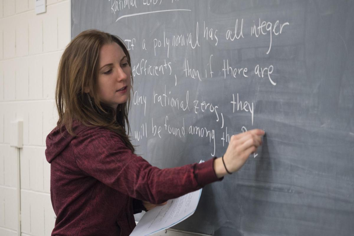 An instructor writing on a chalkboard.