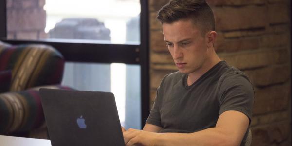 Male student using his Apple laptop