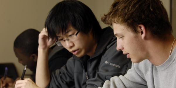 Two students work together on a written assignment.