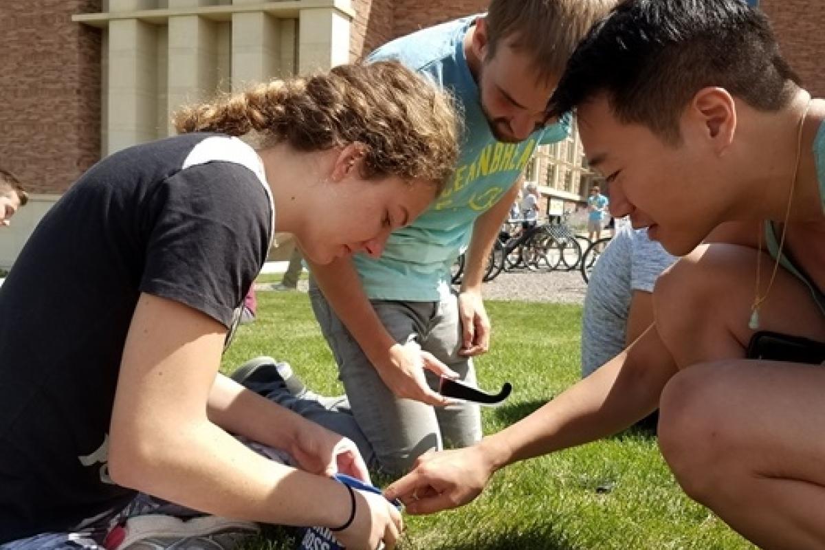 Three people in front of the biotech building