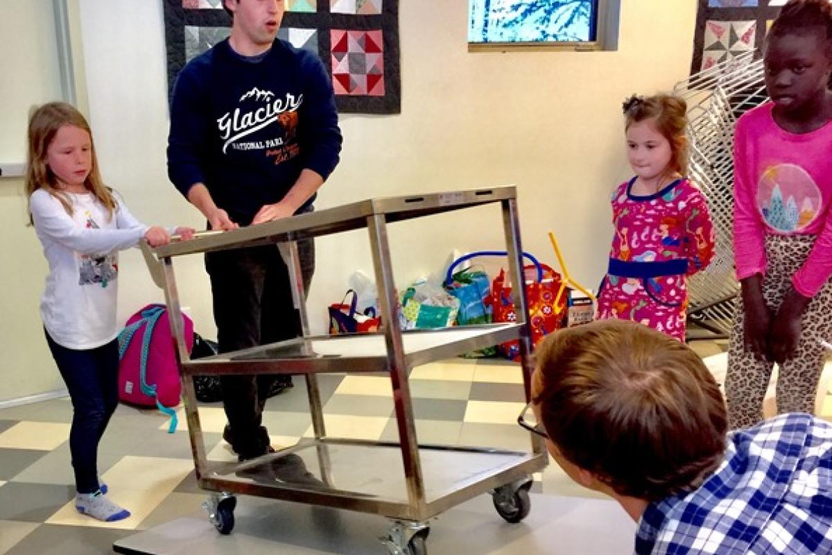 Tom at an outreach event, pushing a cart on an inclined surface