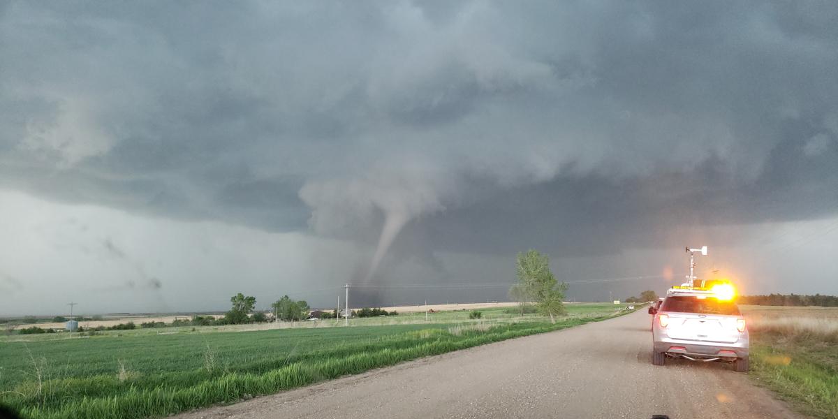 TORUS Vehicles stop at the side of the road as a tornado funnel forms to the left