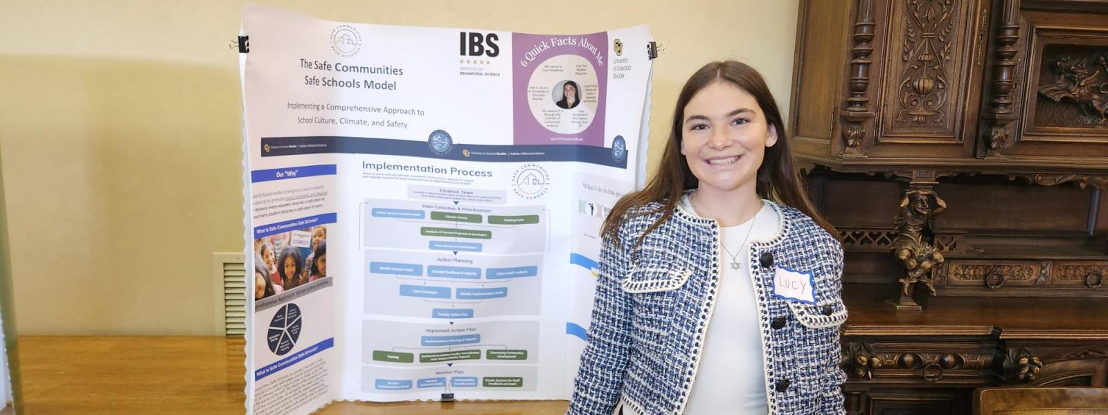 A student smiles next to her poster.