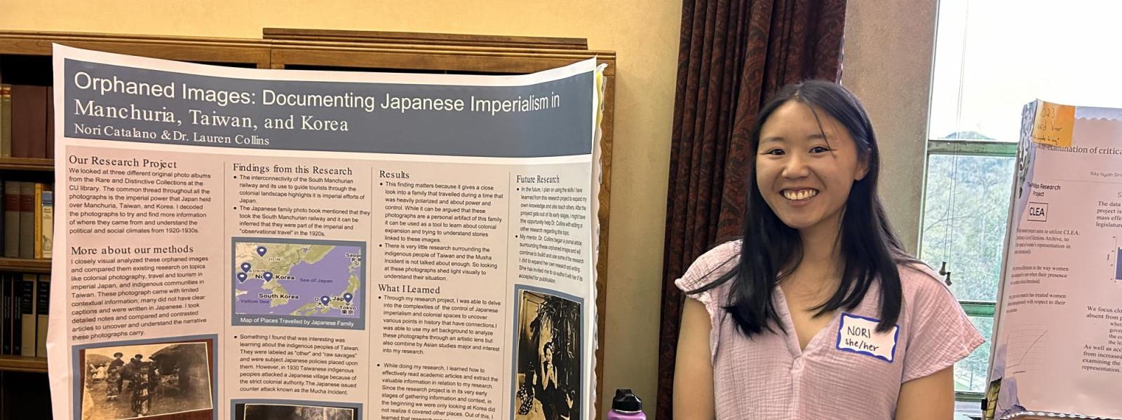 A student smiles and poses next to her poster.